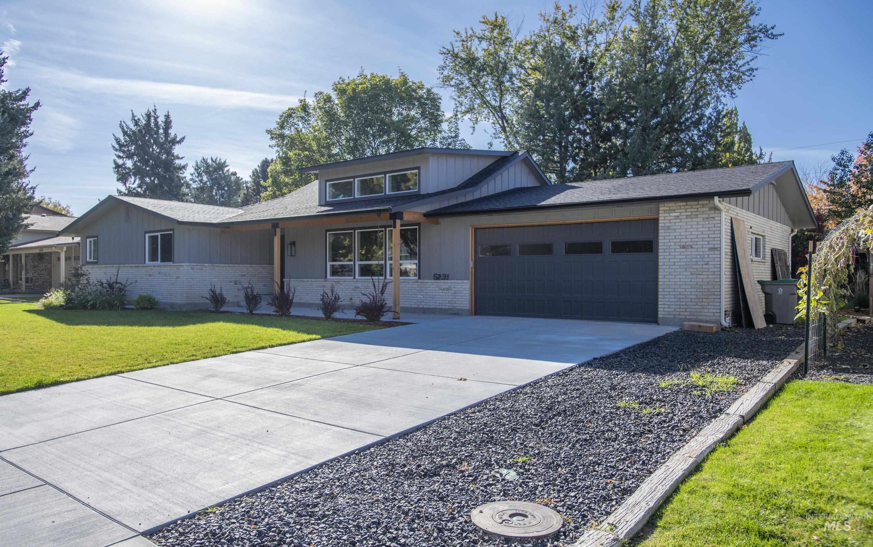 View of front of home with a front yard, driveway, brick siding, and an attached garage