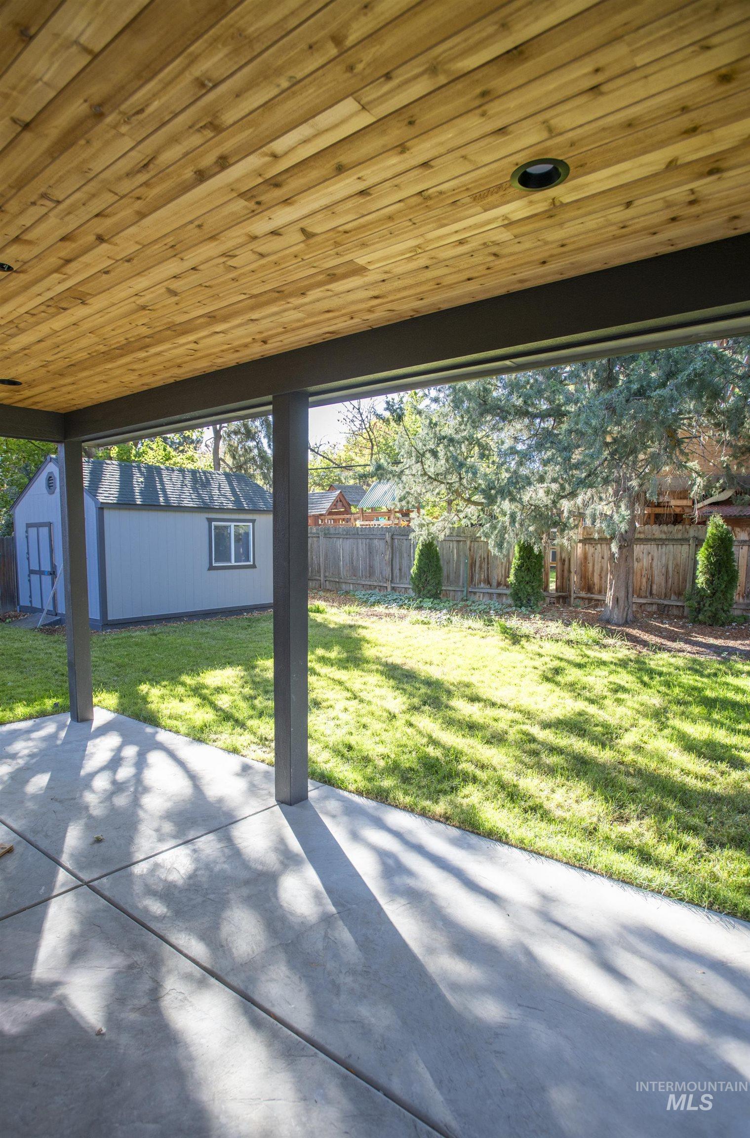 Fenced backyard featuring a patio area and a shed
