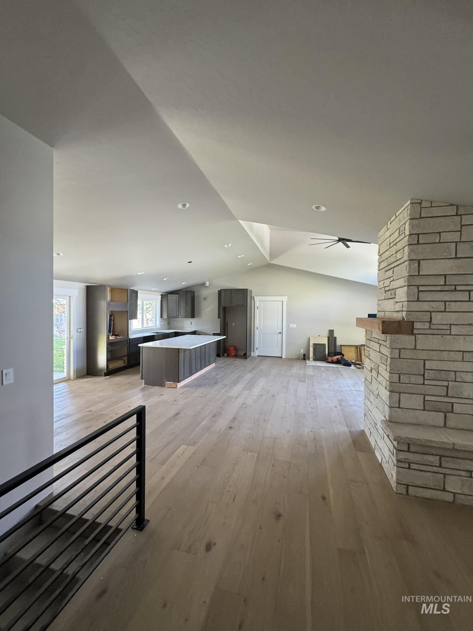 Unfurnished living room featuring lofted ceiling, light wood-style flooring, and ceiling fan
