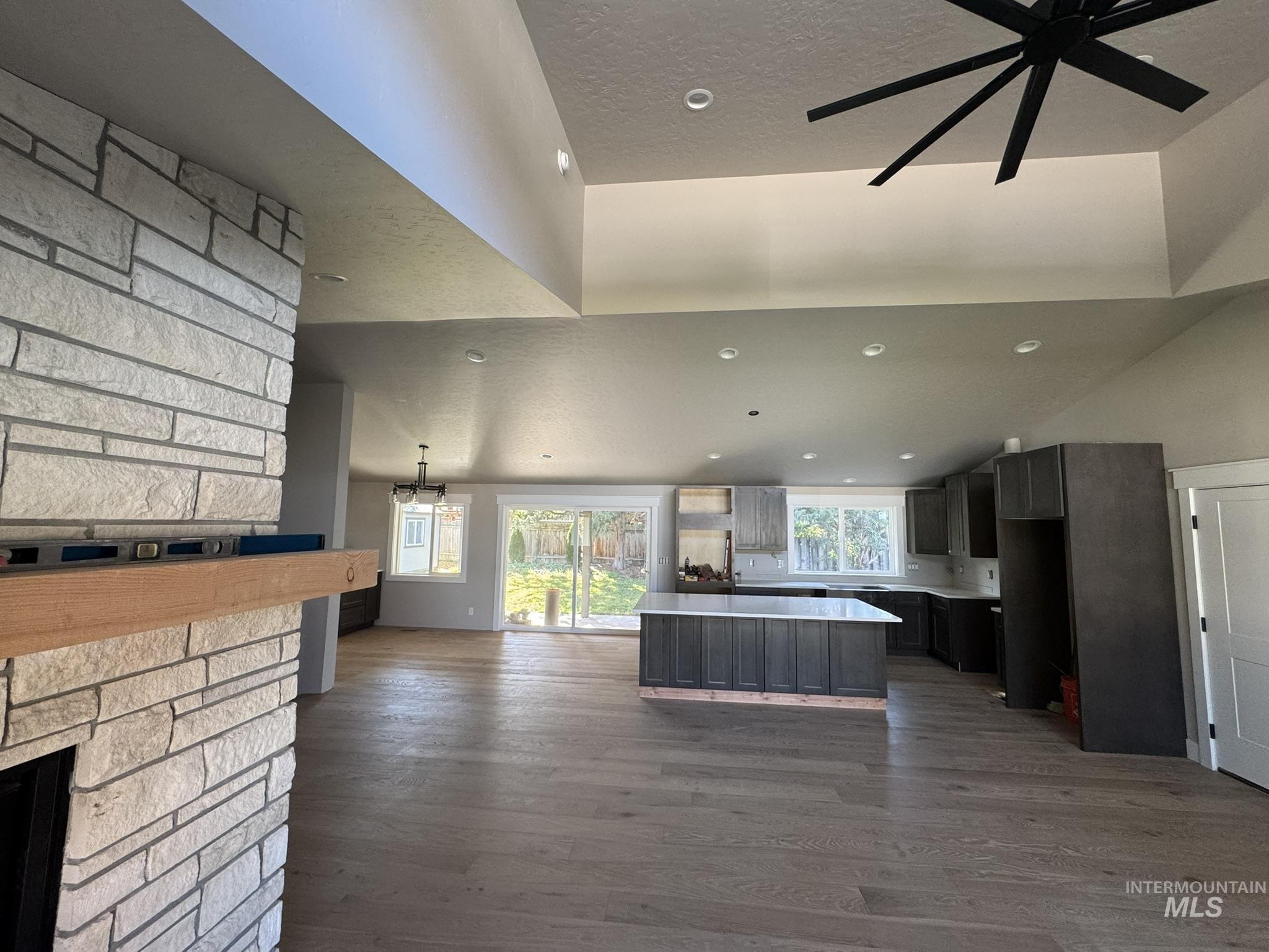 Kitchen featuring open floor plan, lofted ceiling, a kitchen island, light countertops, and dark wood-type flooring