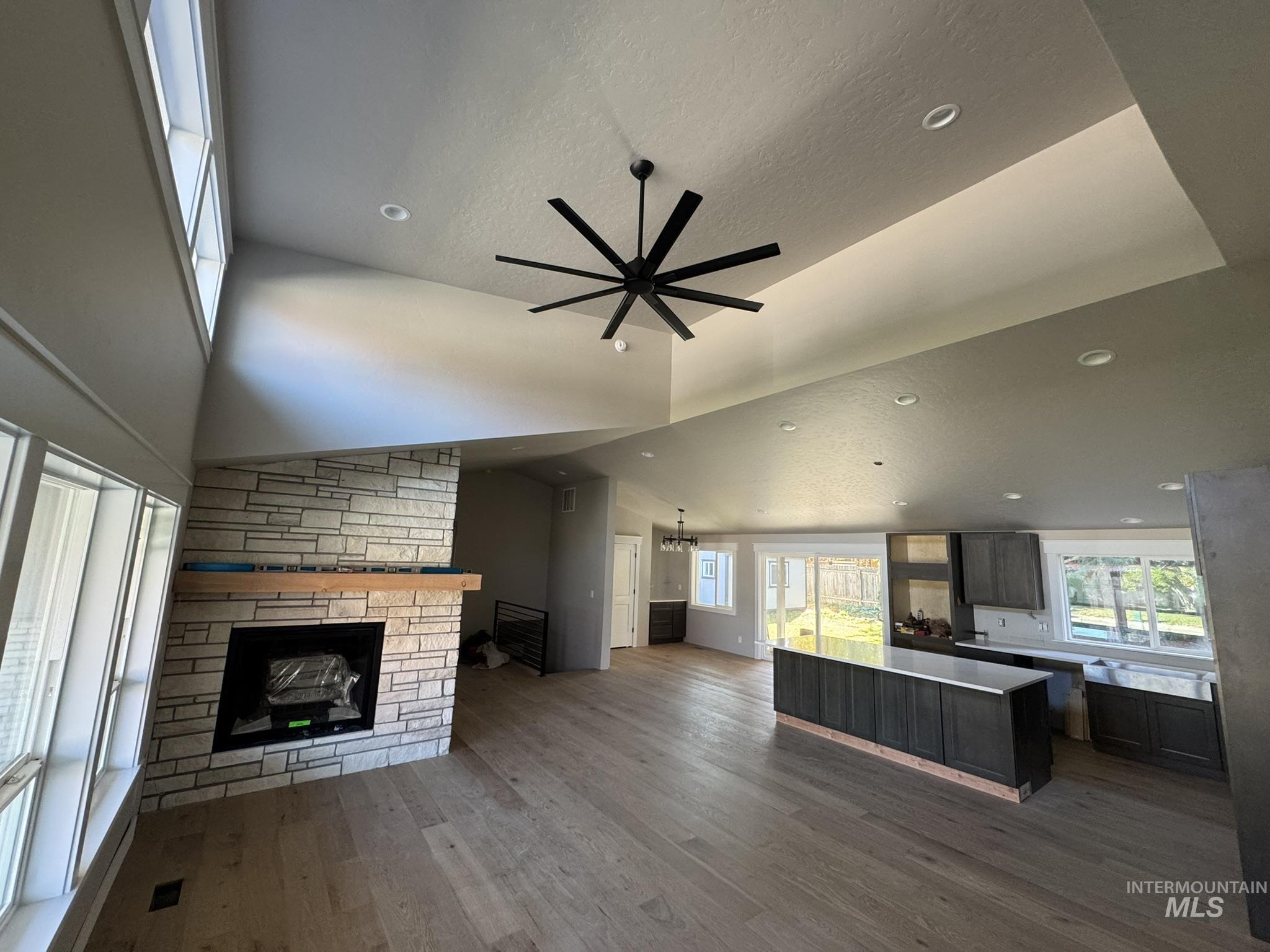 Unfurnished living room featuring healthy amount of natural light, dark wood-style floors, a textured ceiling, recessed lighting, and lofted ceiling