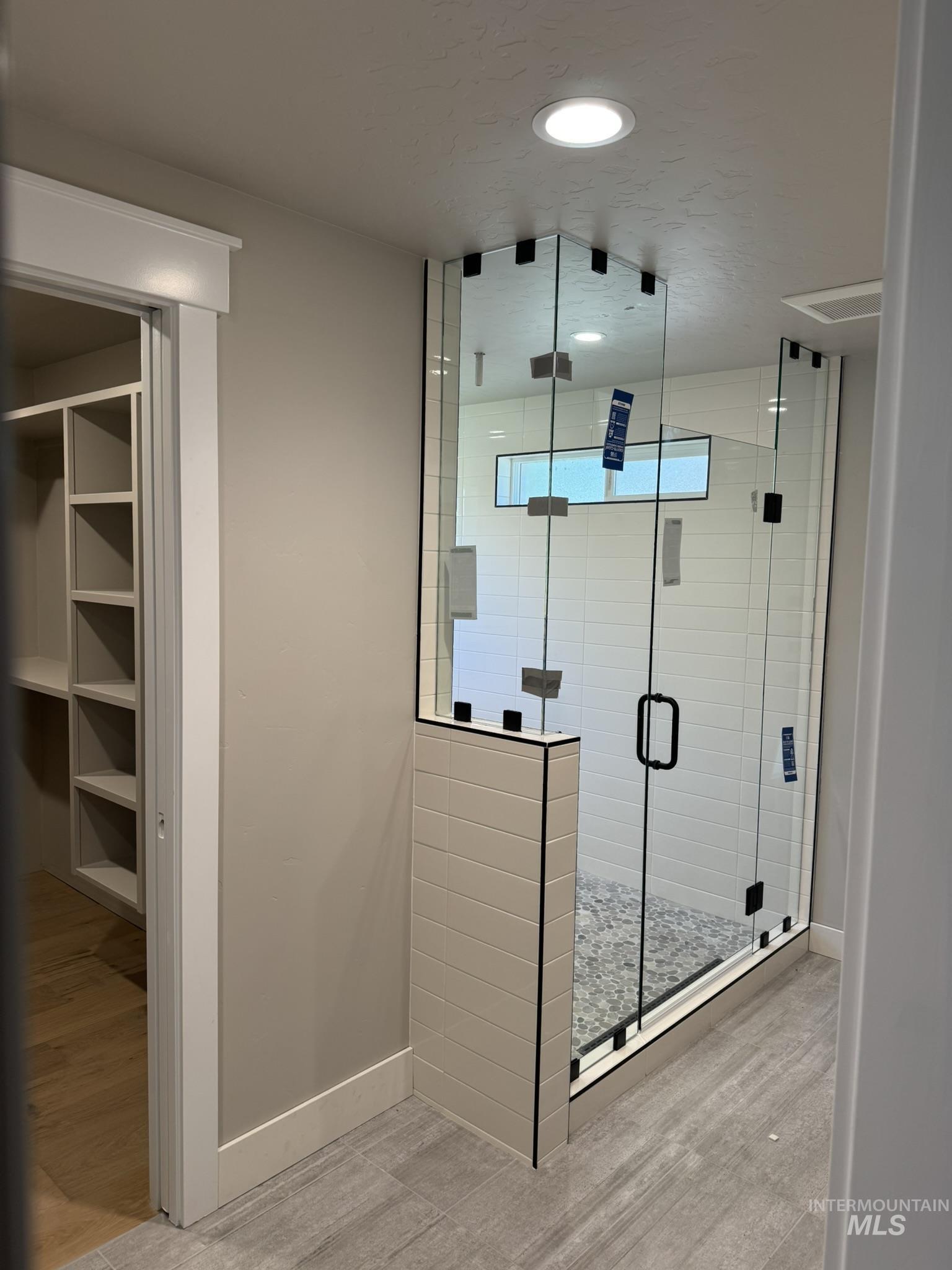 Full bath featuring a wet room, light wood-style flooring, and a spacious closet