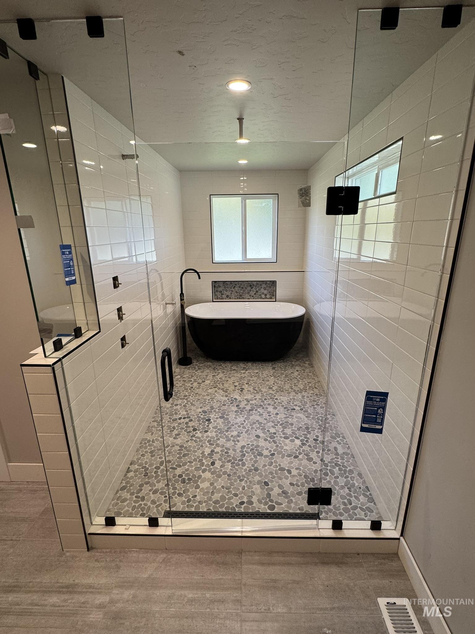 Full bathroom with a freestanding bath, a stall shower, a textured ceiling, and tile patterned flooring
