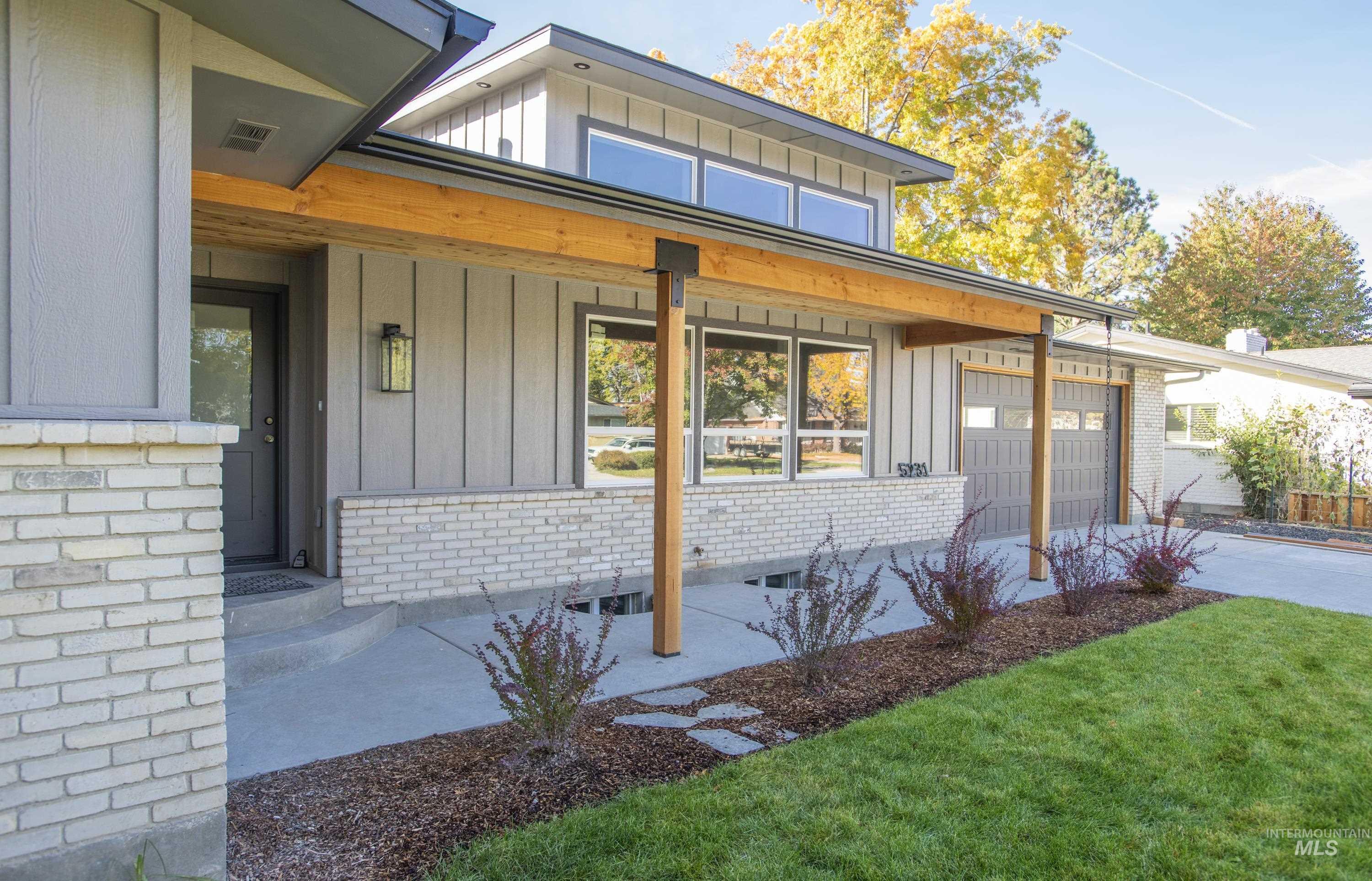 View of front facade with board and batten siding, brick siding, and covered porch