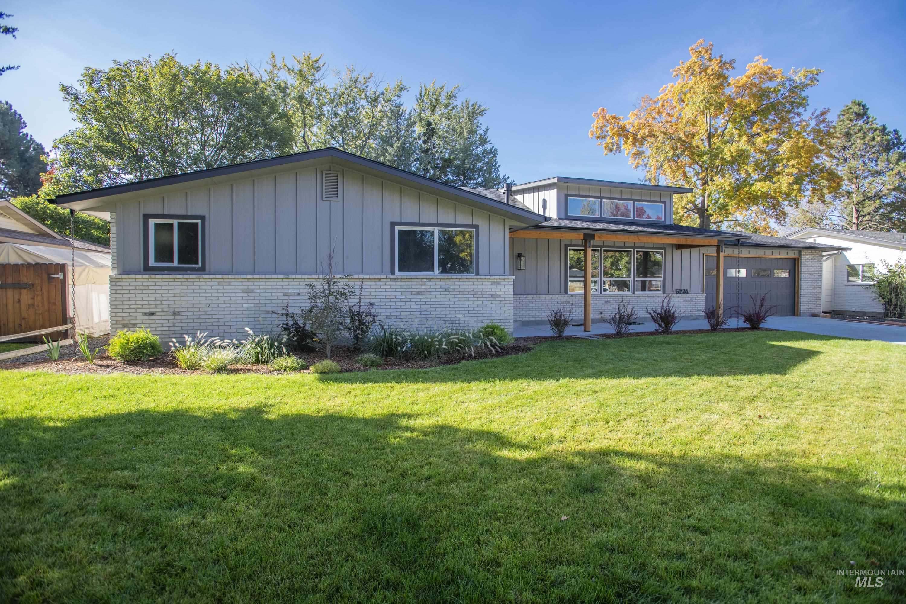 View of front of property with board and batten siding, brick siding, and an attached garage