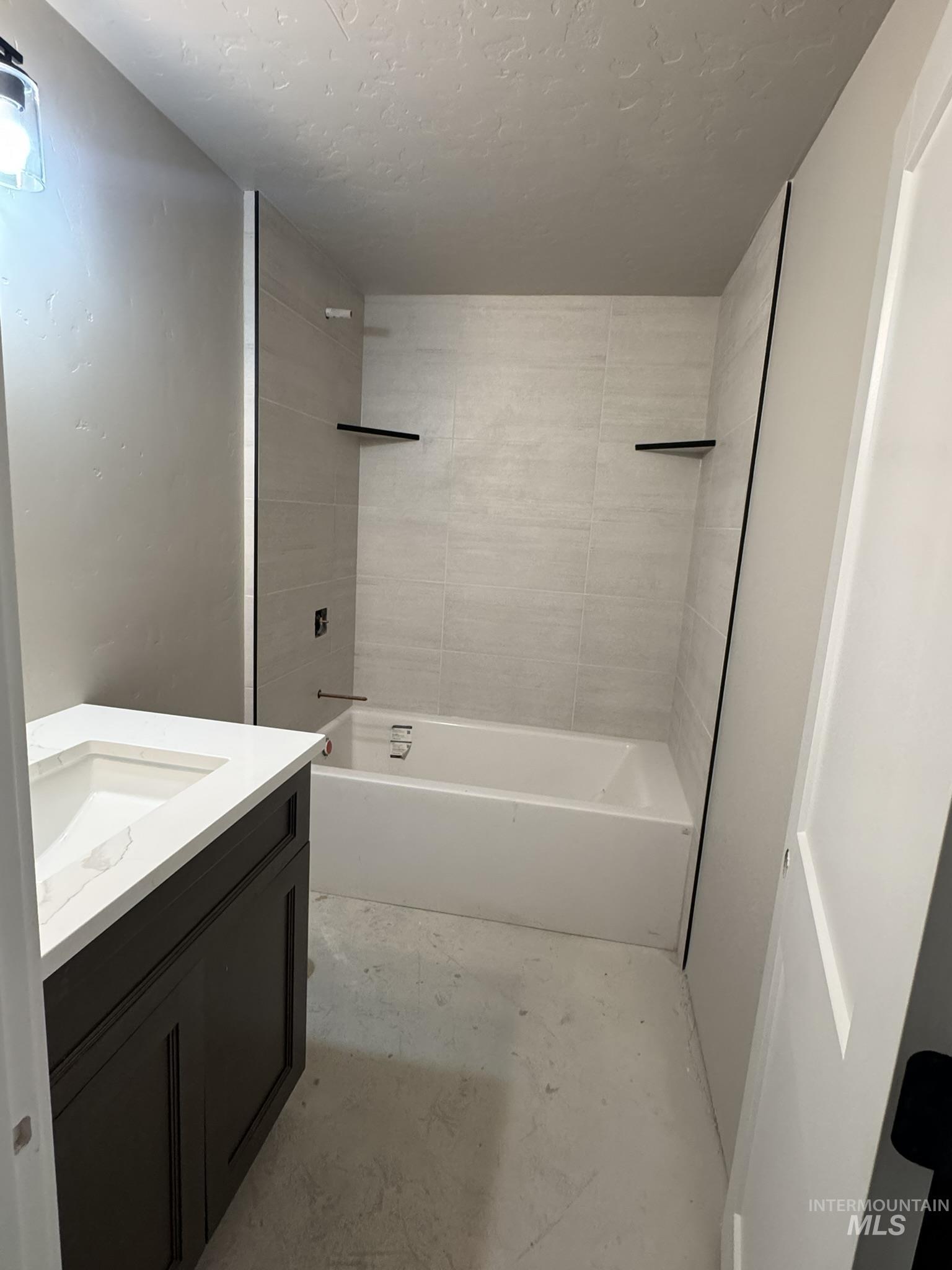 Full bathroom featuring vanity, shower / bathtub combination, and a textured ceiling