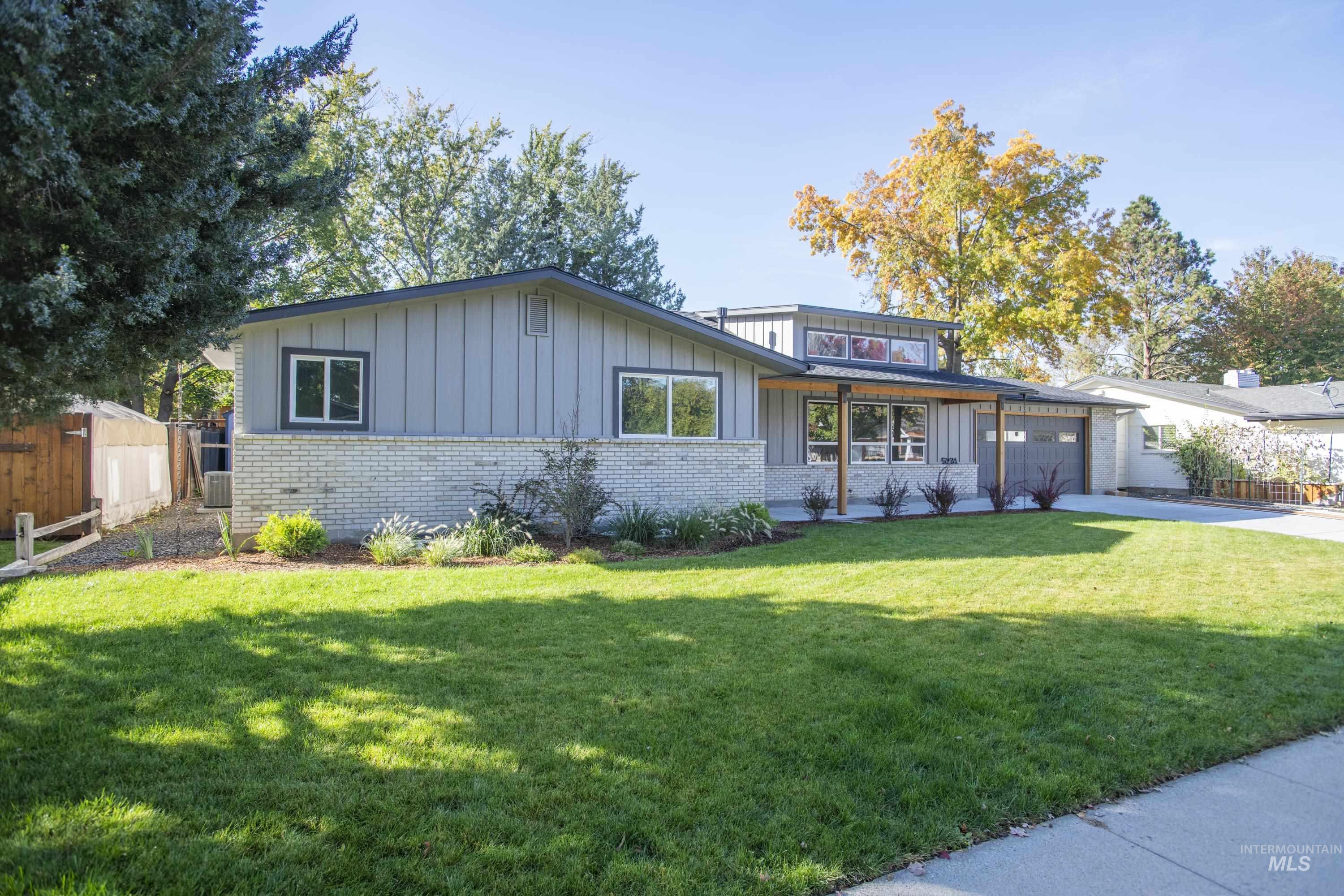View of front facade with board and batten siding, brick siding, an attached garage, and driveway