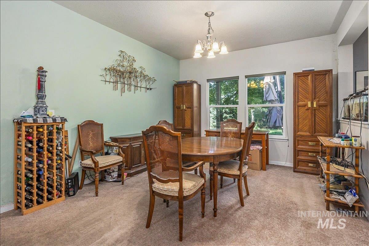 Dining area featuring light carpet, a chandelier, and a textured ceiling
