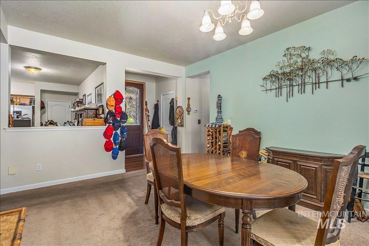 Dining room featuring a textured ceiling, a chandelier, and light colored carpet