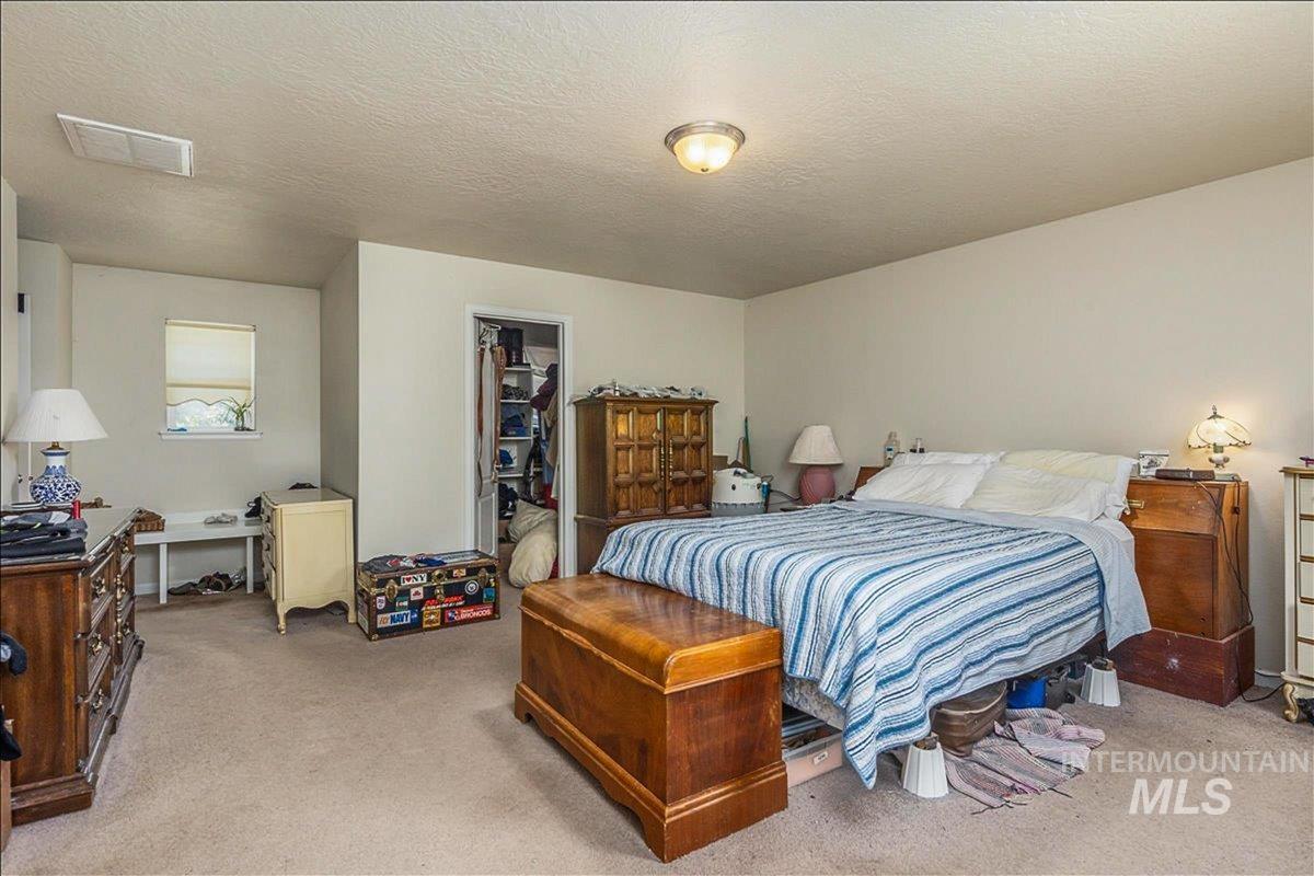 Bedroom with a textured ceiling, a spacious closet, and light colored carpet