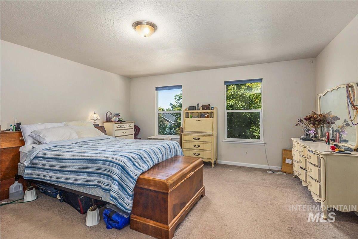 Bedroom featuring a textured ceiling and light colored carpet