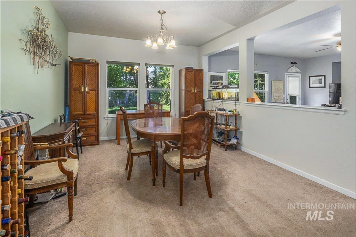 Dining space with light carpet, a textured ceiling, and a chandelier
