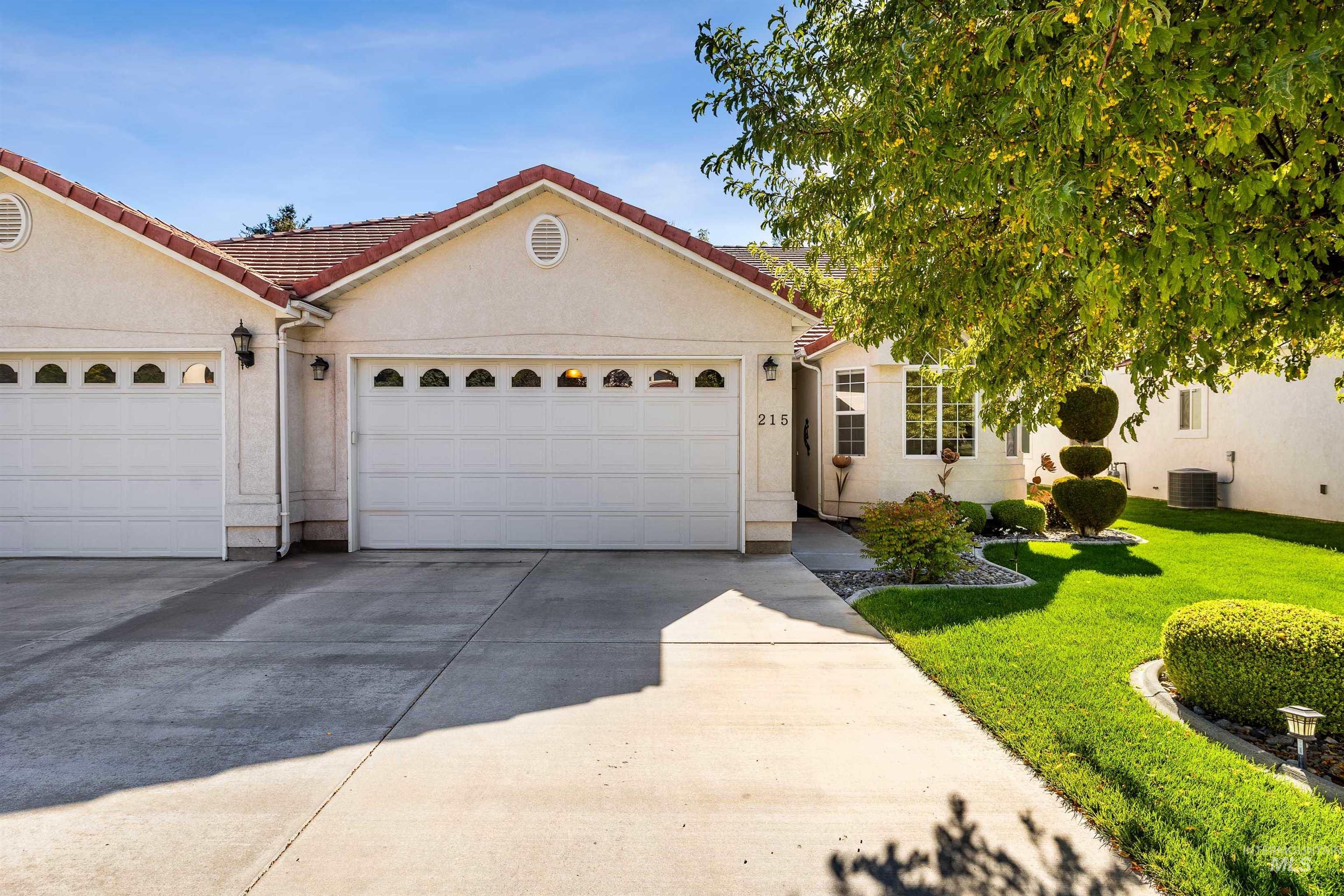 View of front of home with driveway, stucco siding, a tile roof, an attached garage, and a front yard