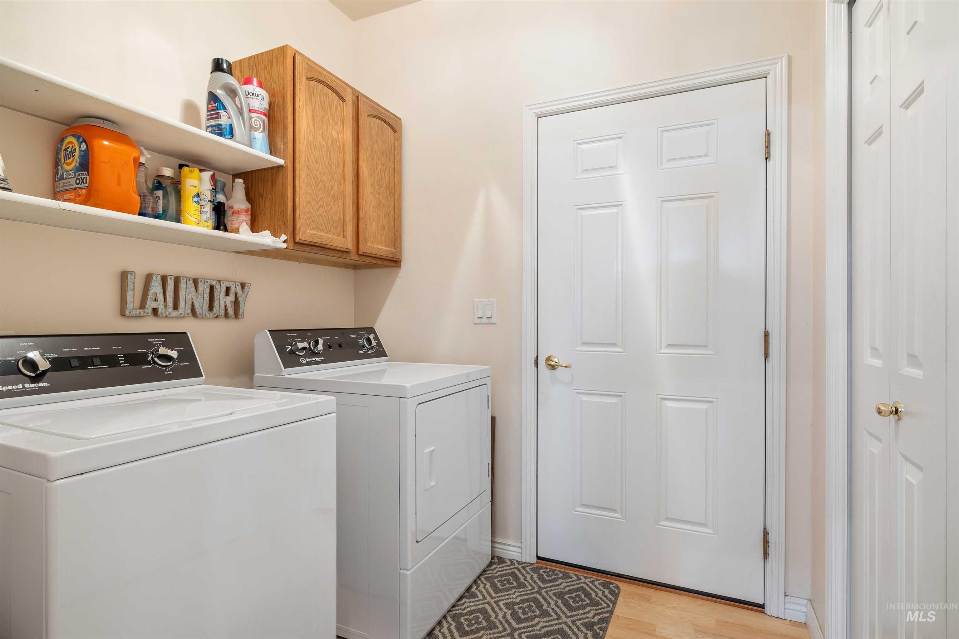 Laundry room with independent washer and dryer, cabinet space, and light wood-type flooring