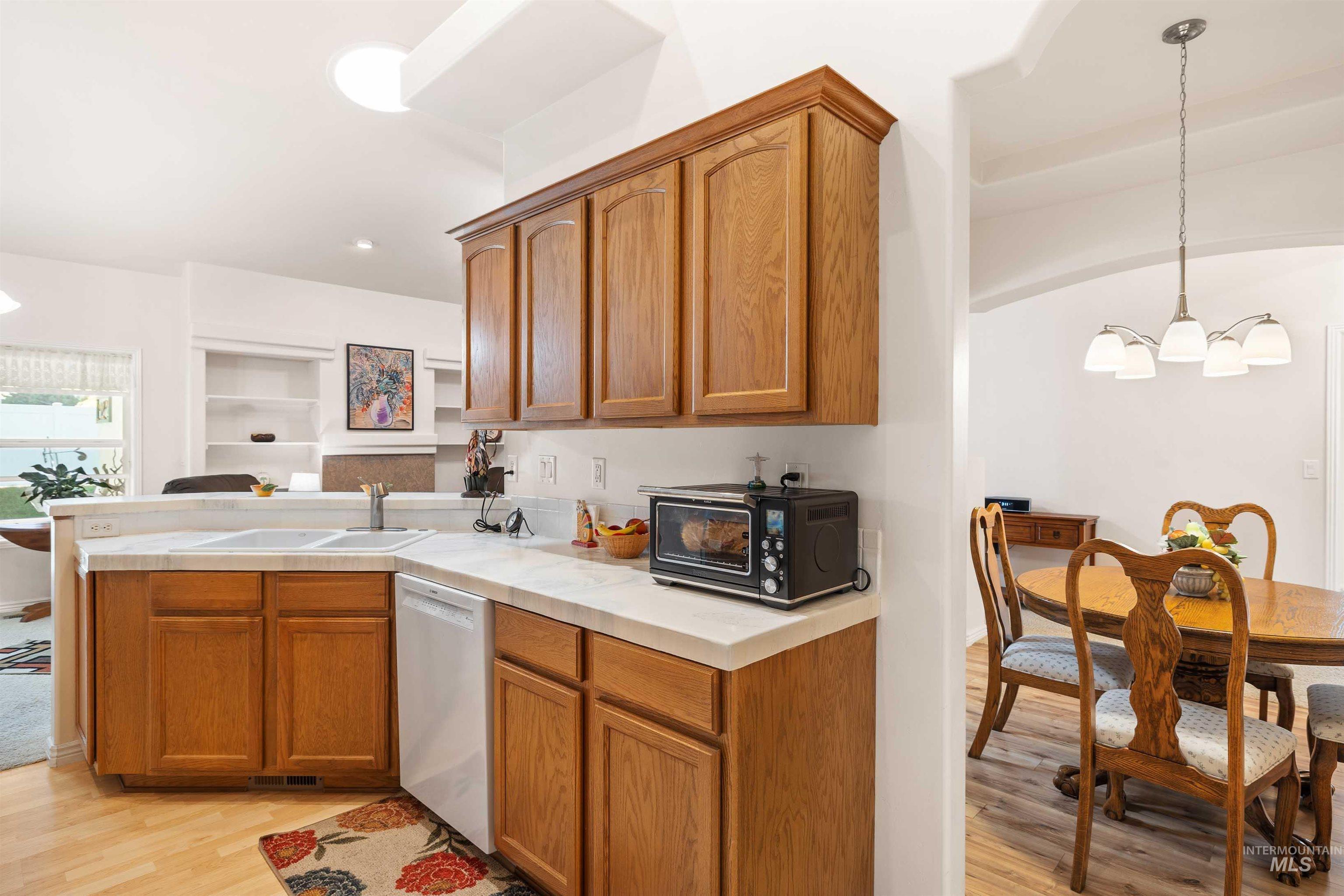 Kitchen with pendant lighting, a chandelier, light wood-type flooring, brown cabinets, and recessed lighting