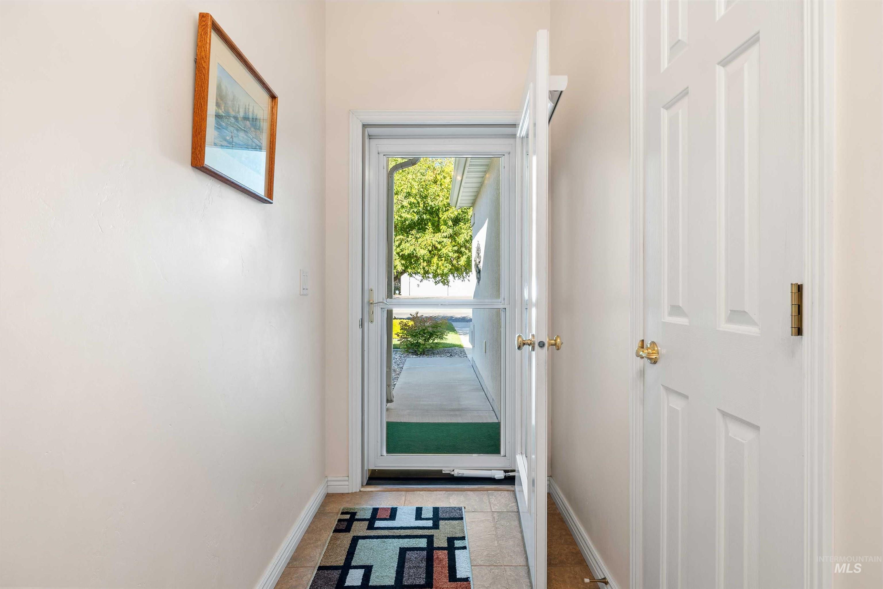 Doorway to outside with tile patterned flooring and baseboards