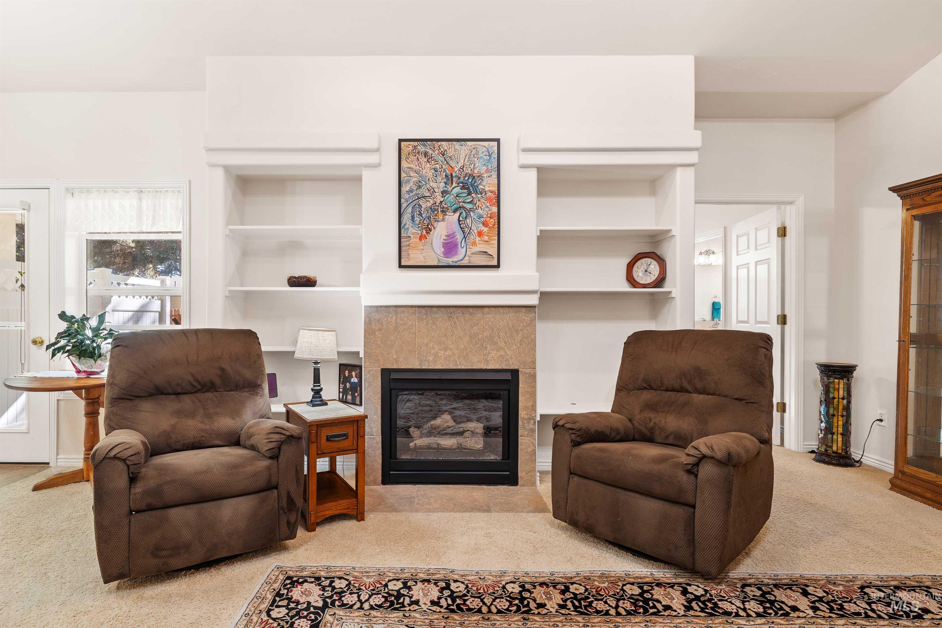 Living area with light colored carpet, a fireplace, and built in features