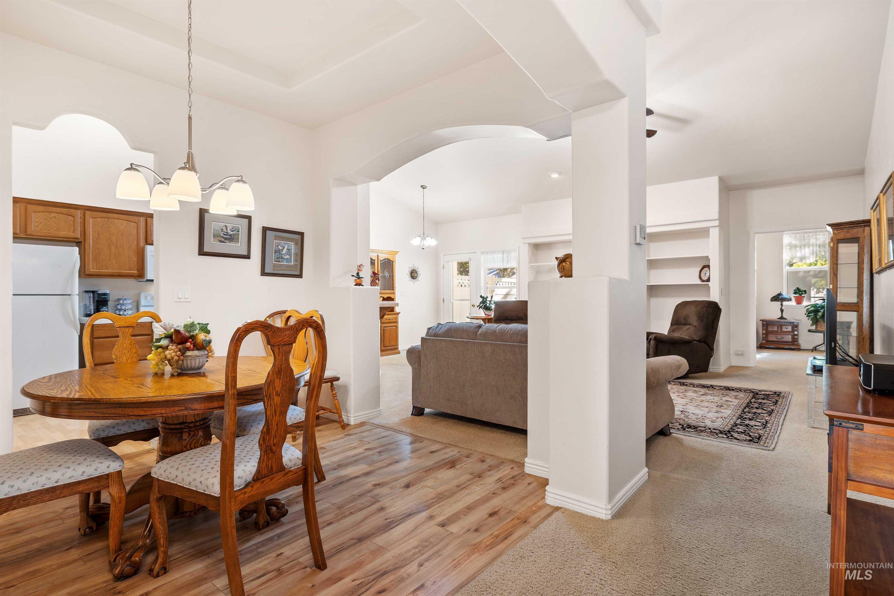 Dining space featuring a chandelier, arched walkways, and light wood-style flooring
