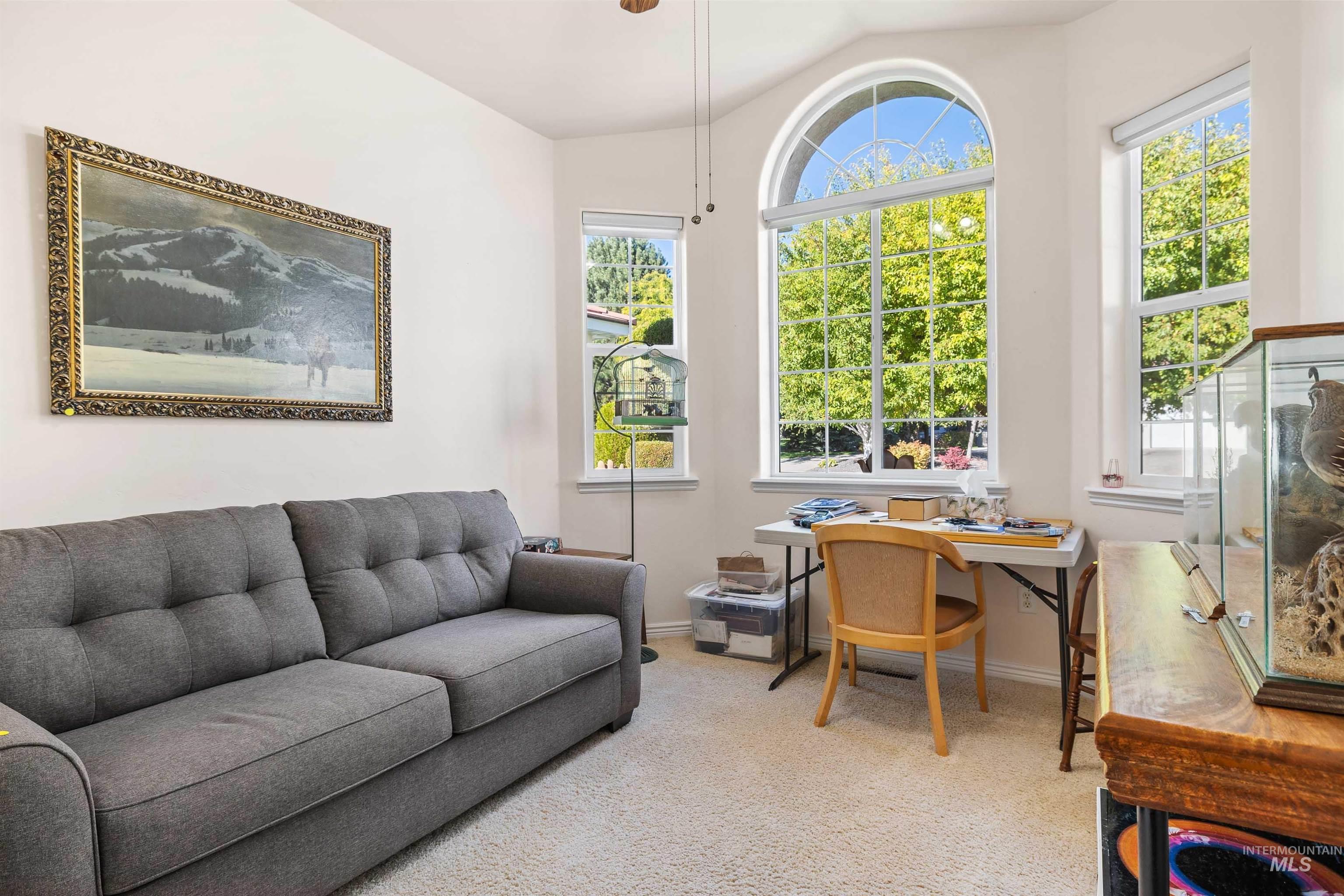 Home office with light colored carpet, lofted ceiling, and ceiling fan