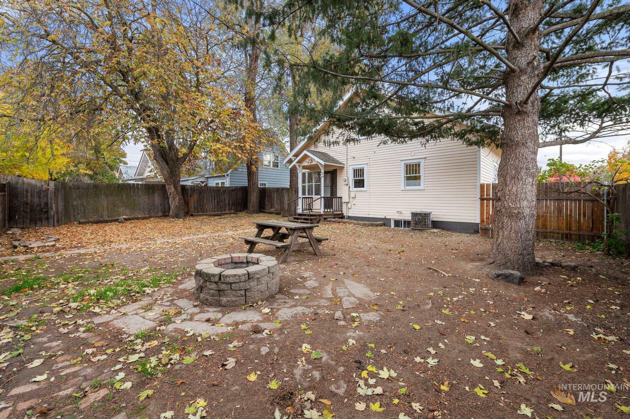 Back of property with a fenced backyard, an outdoor fire pit, and a patio