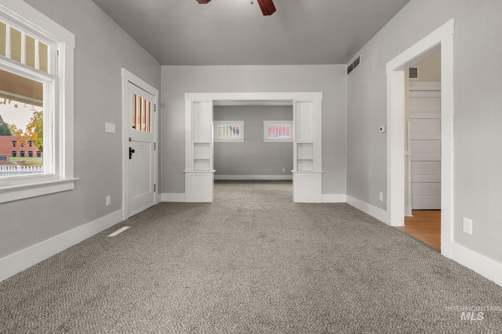 Carpeted spare room featuring ceiling fan and baseboards