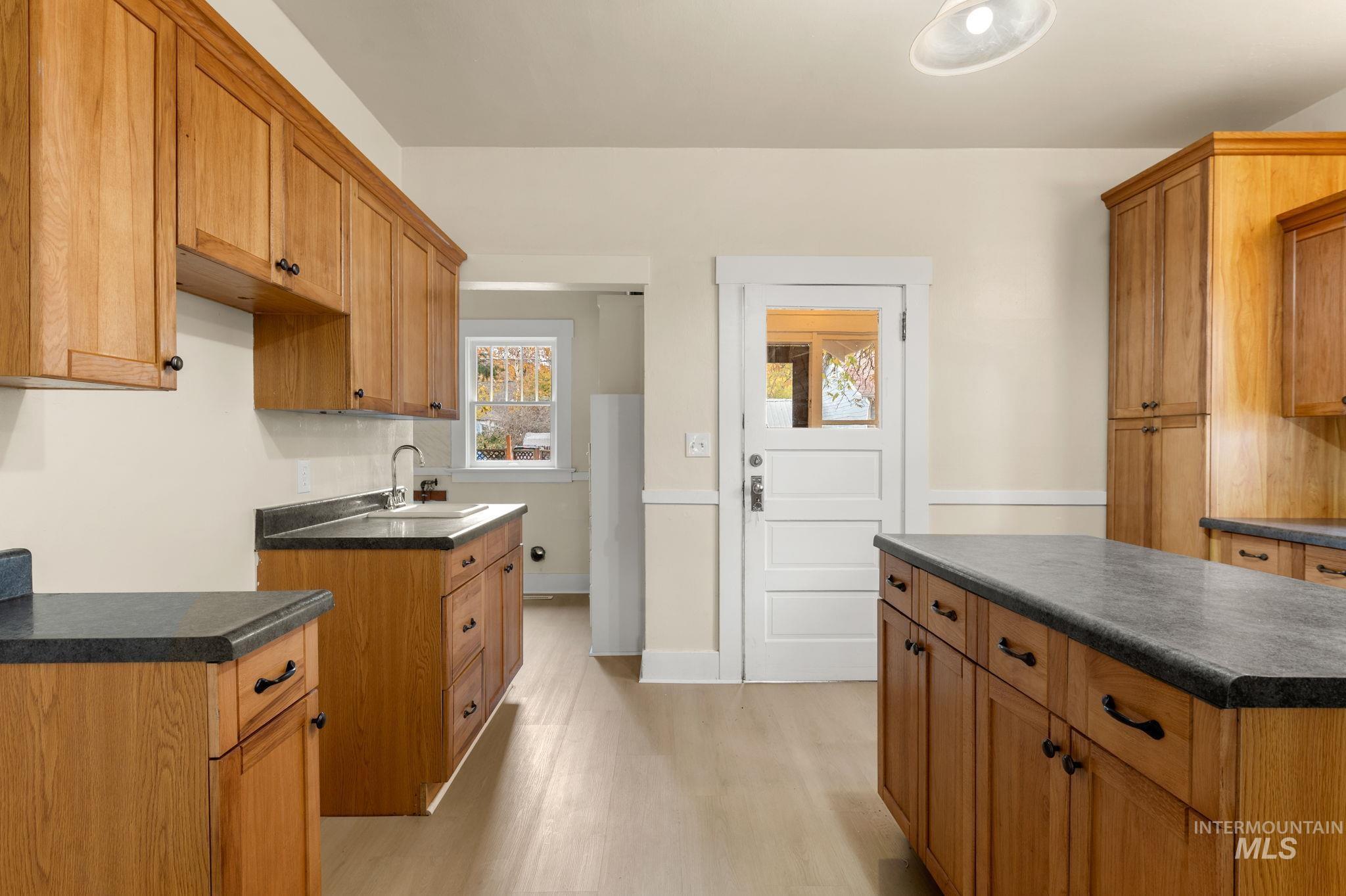 Kitchen with dark countertops, light wood finished floors, brown cabinets, and a kitchen island
