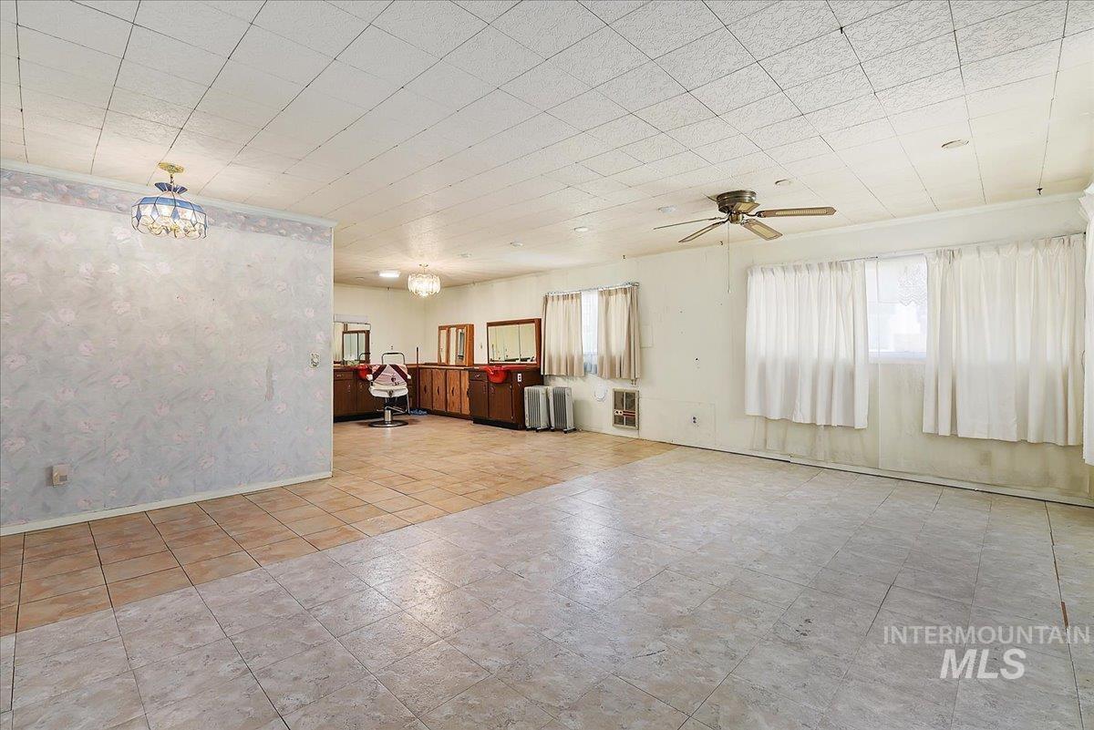 Open-concept interior featuring mixed tile flooring, a textured ceiling with a ceiling fan, and multiple windows with white curtains