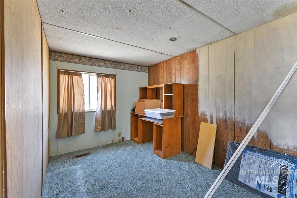 Room featuring paneling walls, a window with horizontal blinds, and carpeting