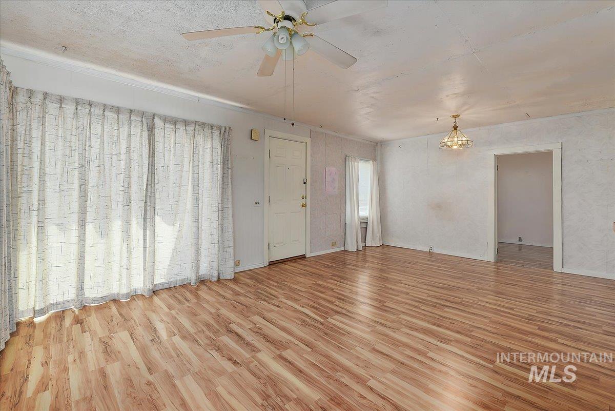 Wood-finish flooring throughout a spacious room with a ceiling fan light fixture