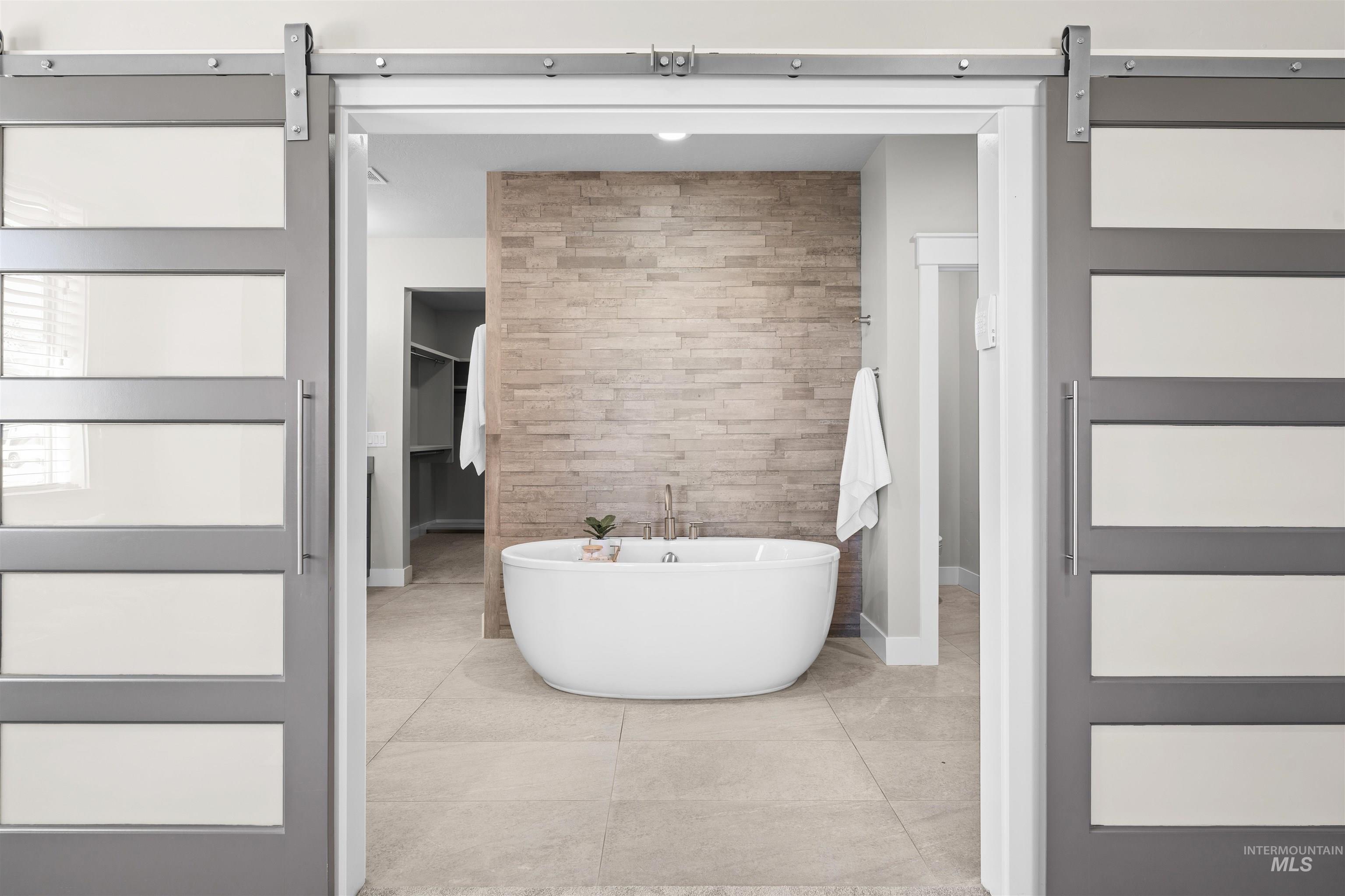 Full bathroom featuring a soaking tub, an accent wall, and a walk in closet