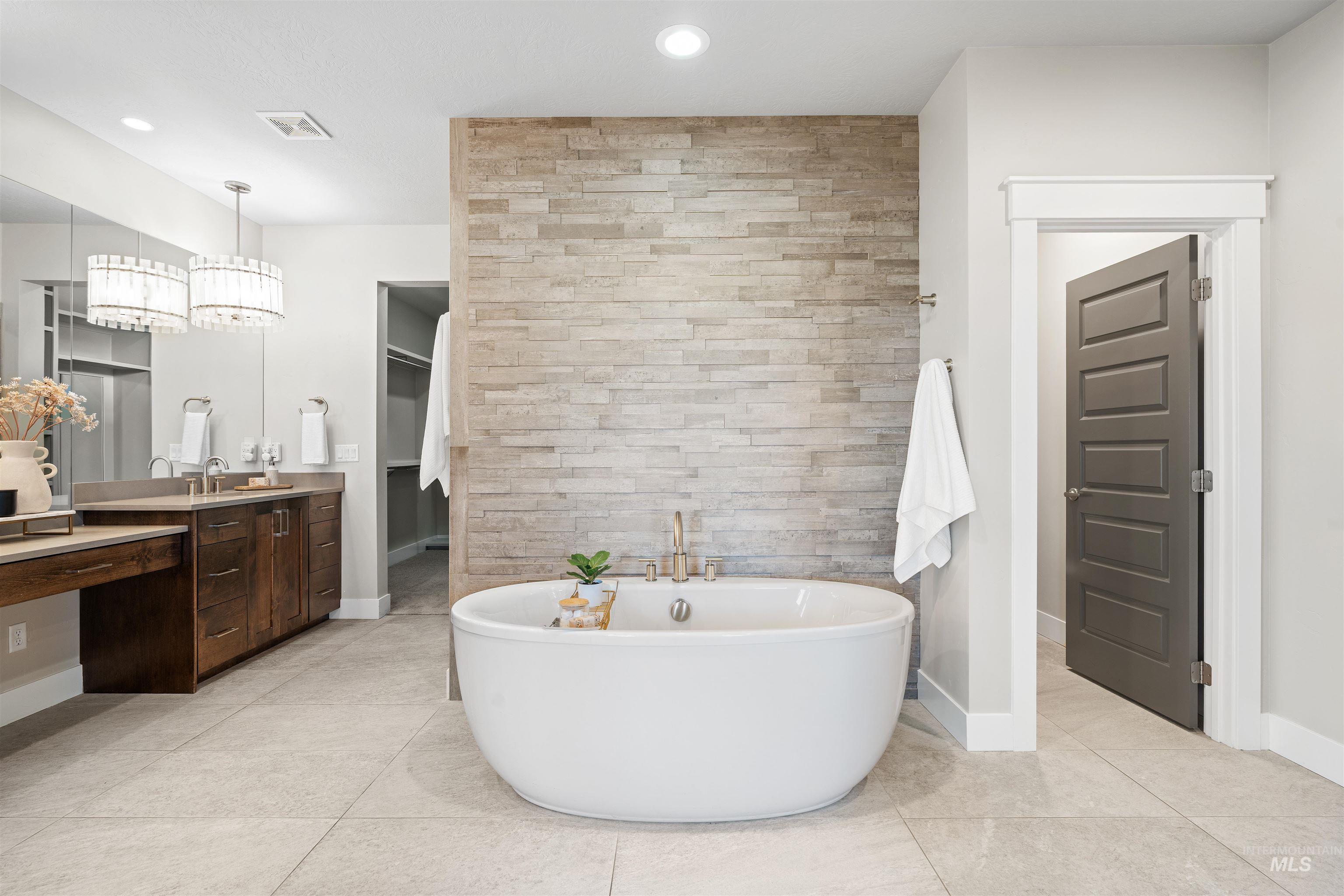 Bathroom with vanity, a freestanding tub, a walk in closet, light tile patterned floors, and recessed lighting
