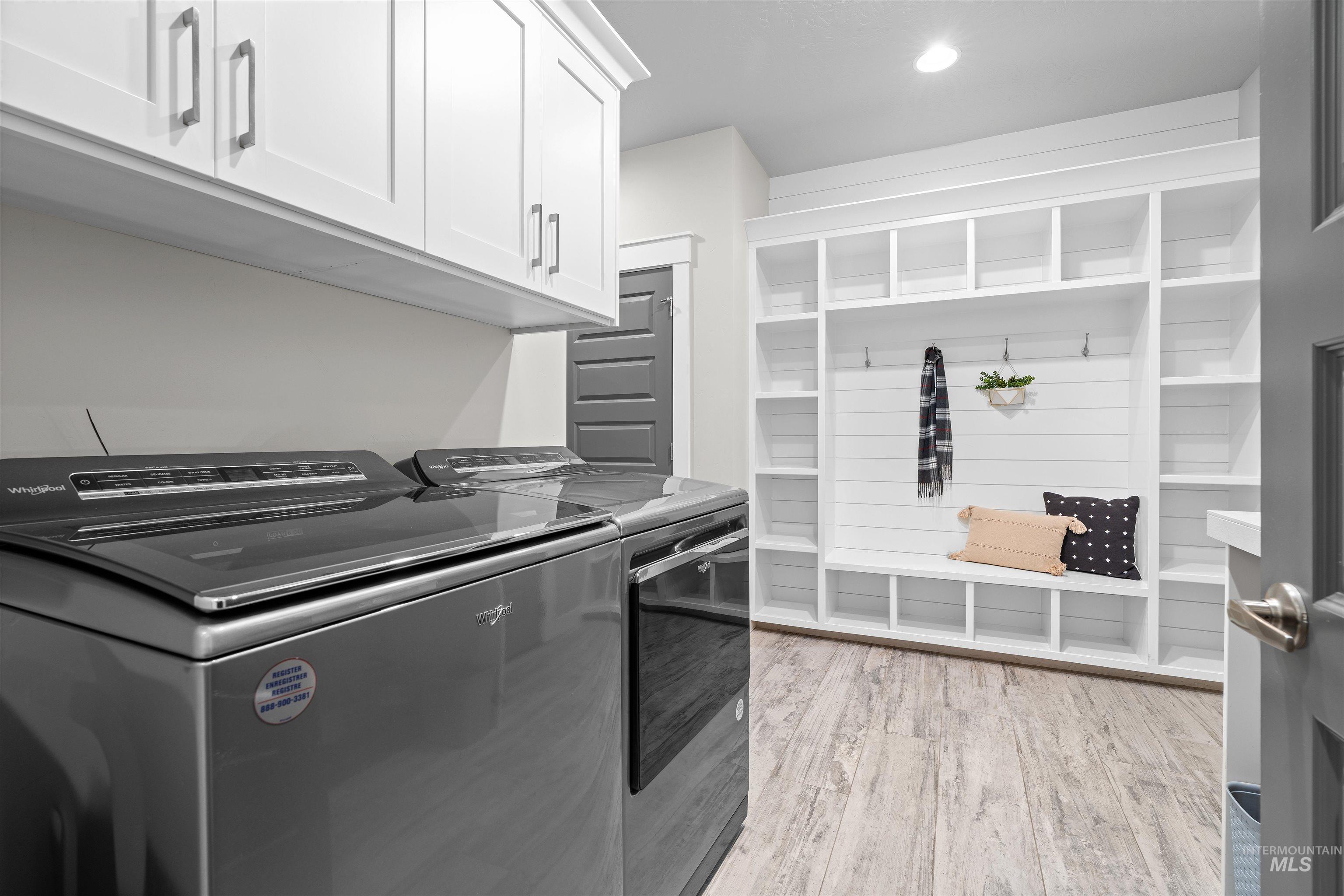 Laundry room featuring light wood finished floors, cabinet space, washer and clothes dryer, and recessed lighting