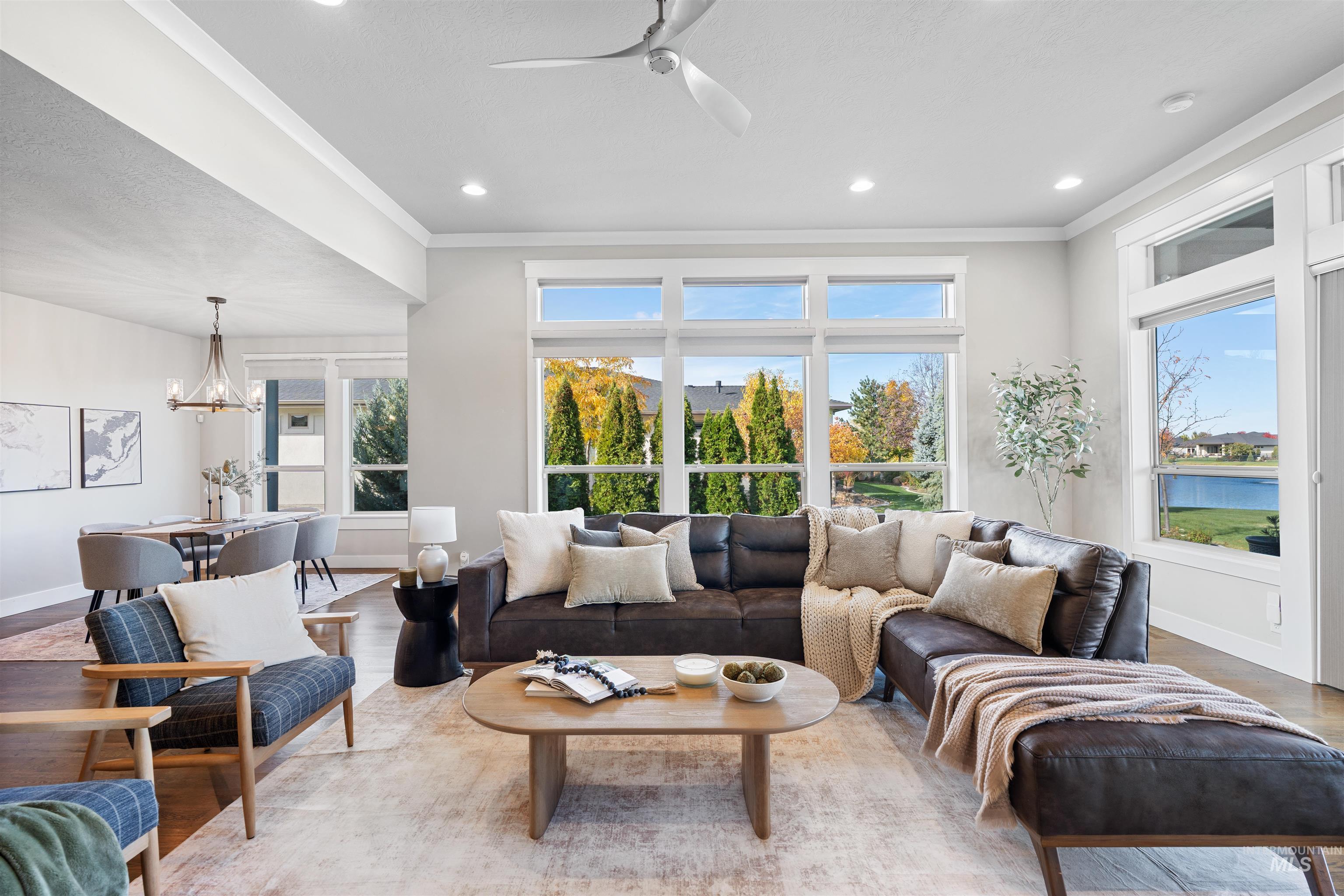 Living area with a ceiling fan, wood finished floors, hanging lights, and crown molding