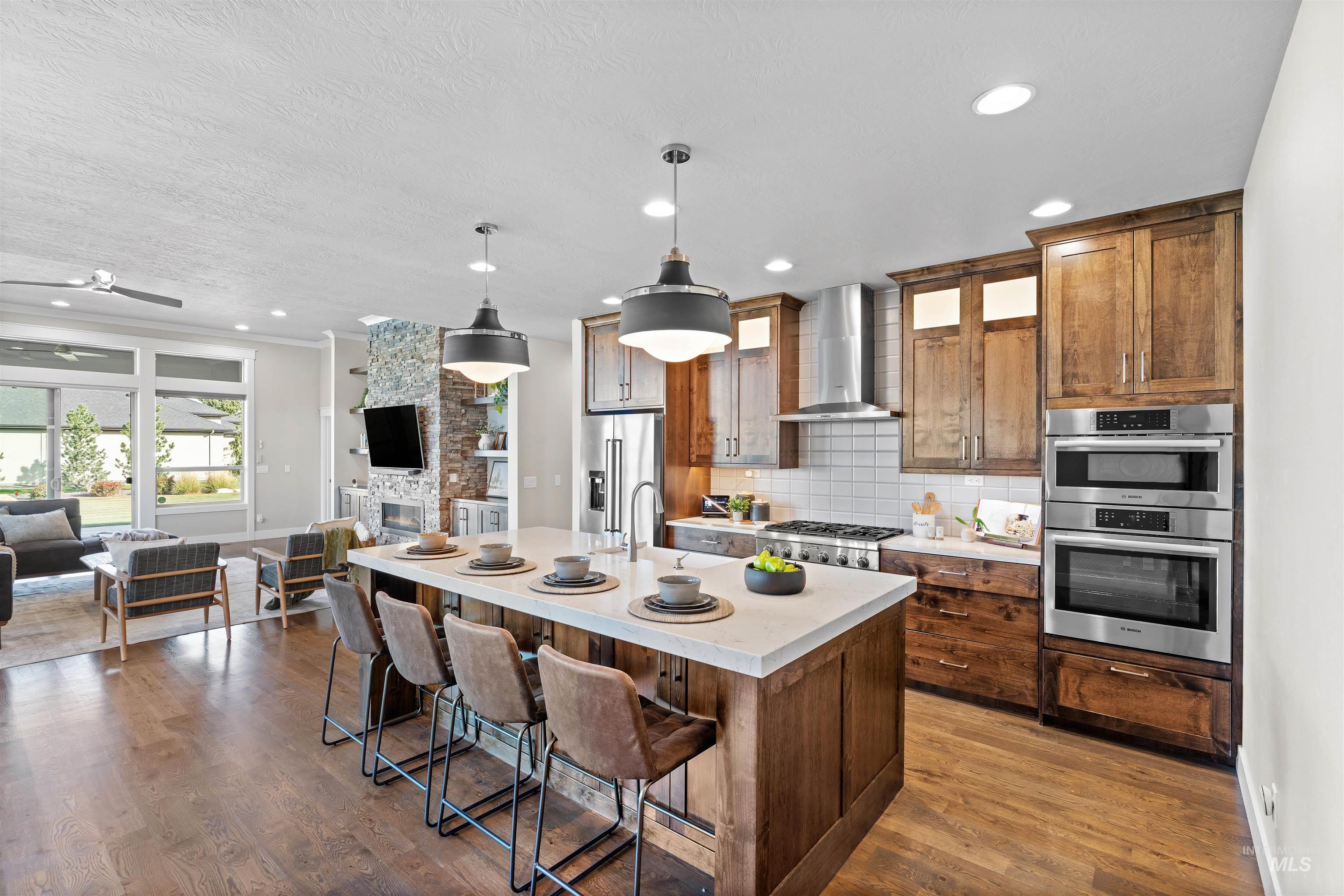 Kitchen featuring open floor plan, a kitchen breakfast bar, hanging light fixtures, stainless steel appliances, and an island with sink