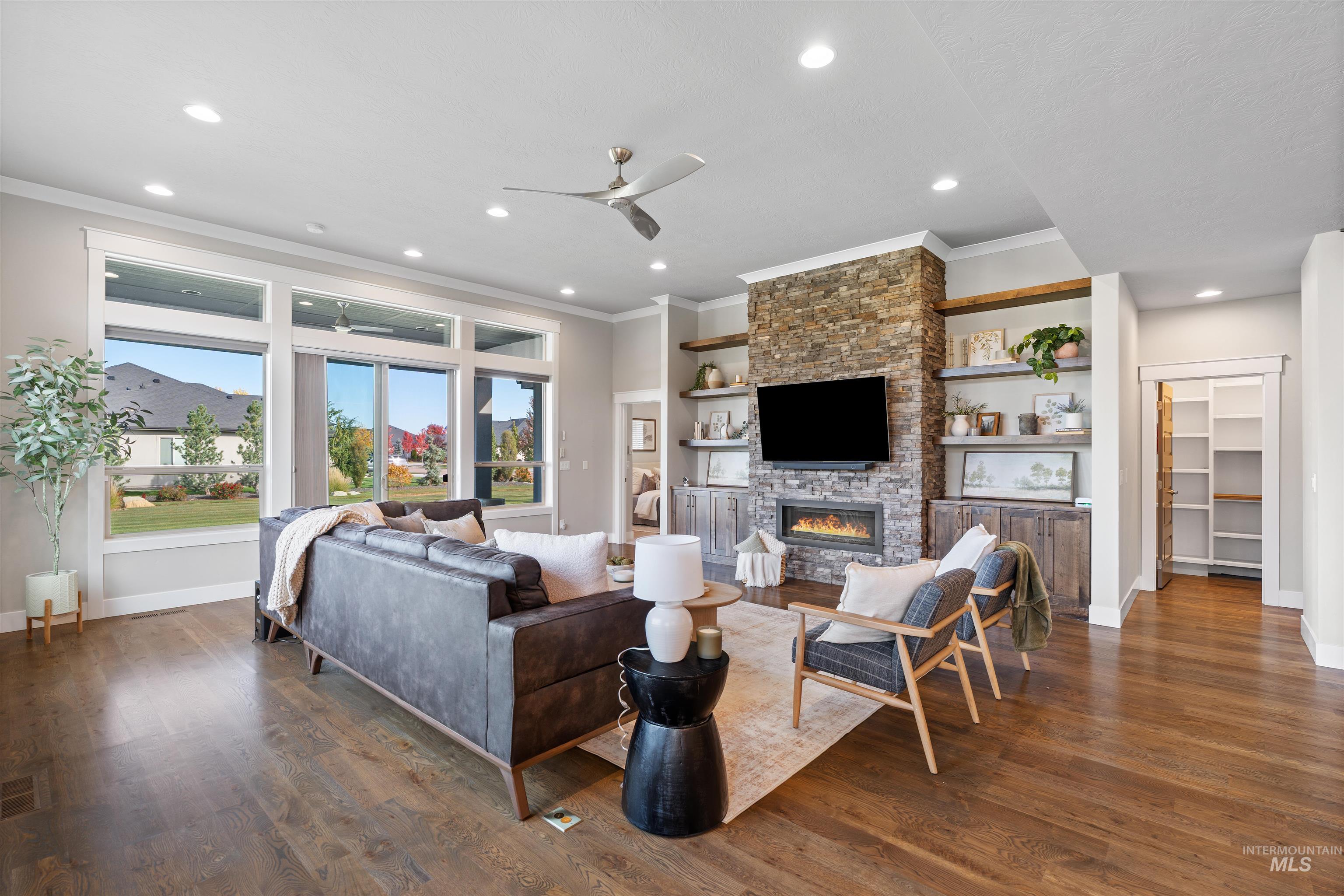 Living room with ceiling fan, dark wood-style floors, a fireplace, ornamental molding, and recessed lighting