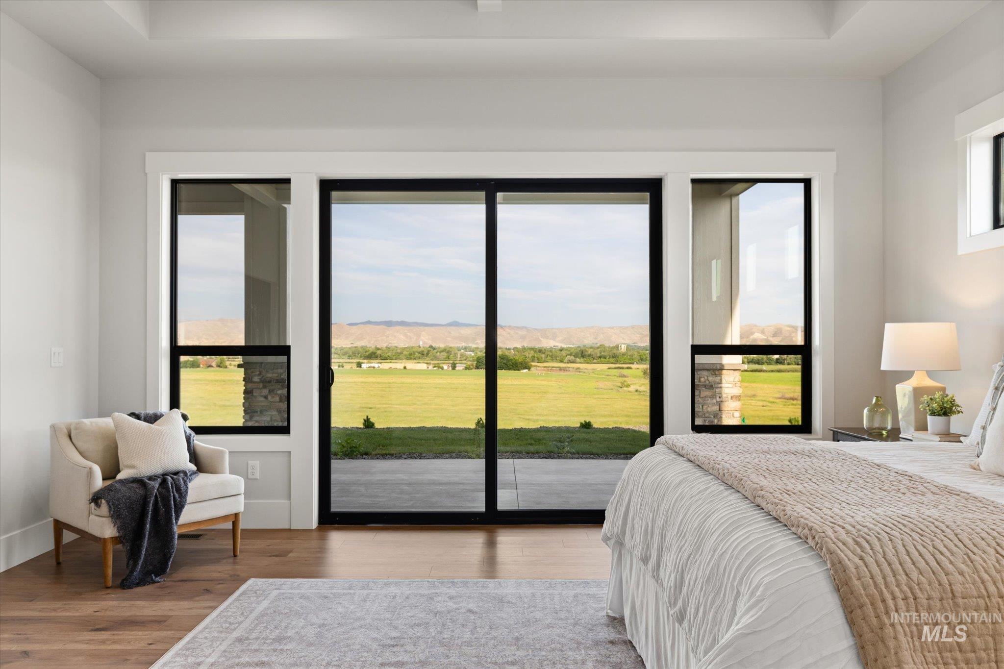 Bedroom featuring wood finished floors, access to outside, and a mountain view