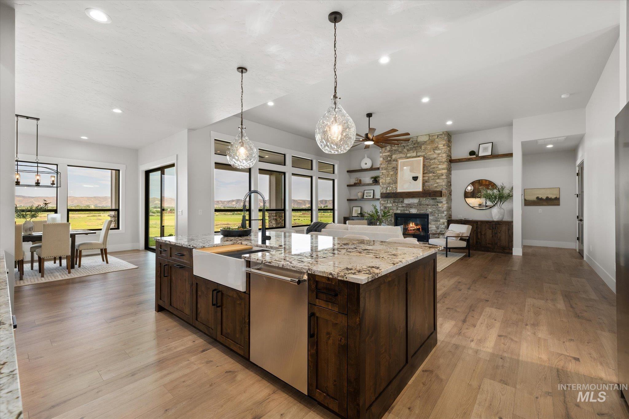 Kitchen featuring dark brown cabinetry, hanging light fixtures, light wood-style floors, light stone countertops, and recessed lighting