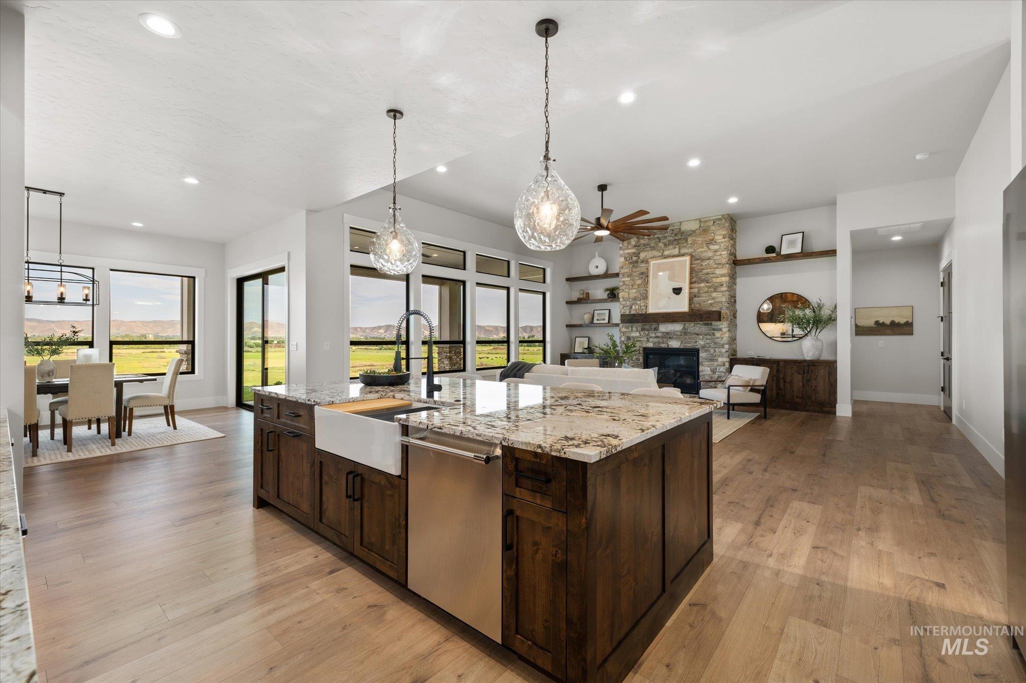 Kitchen featuring dark brown cabinets, hanging light fixtures, light wood-style flooring, stainless steel dishwasher, and recessed lighting