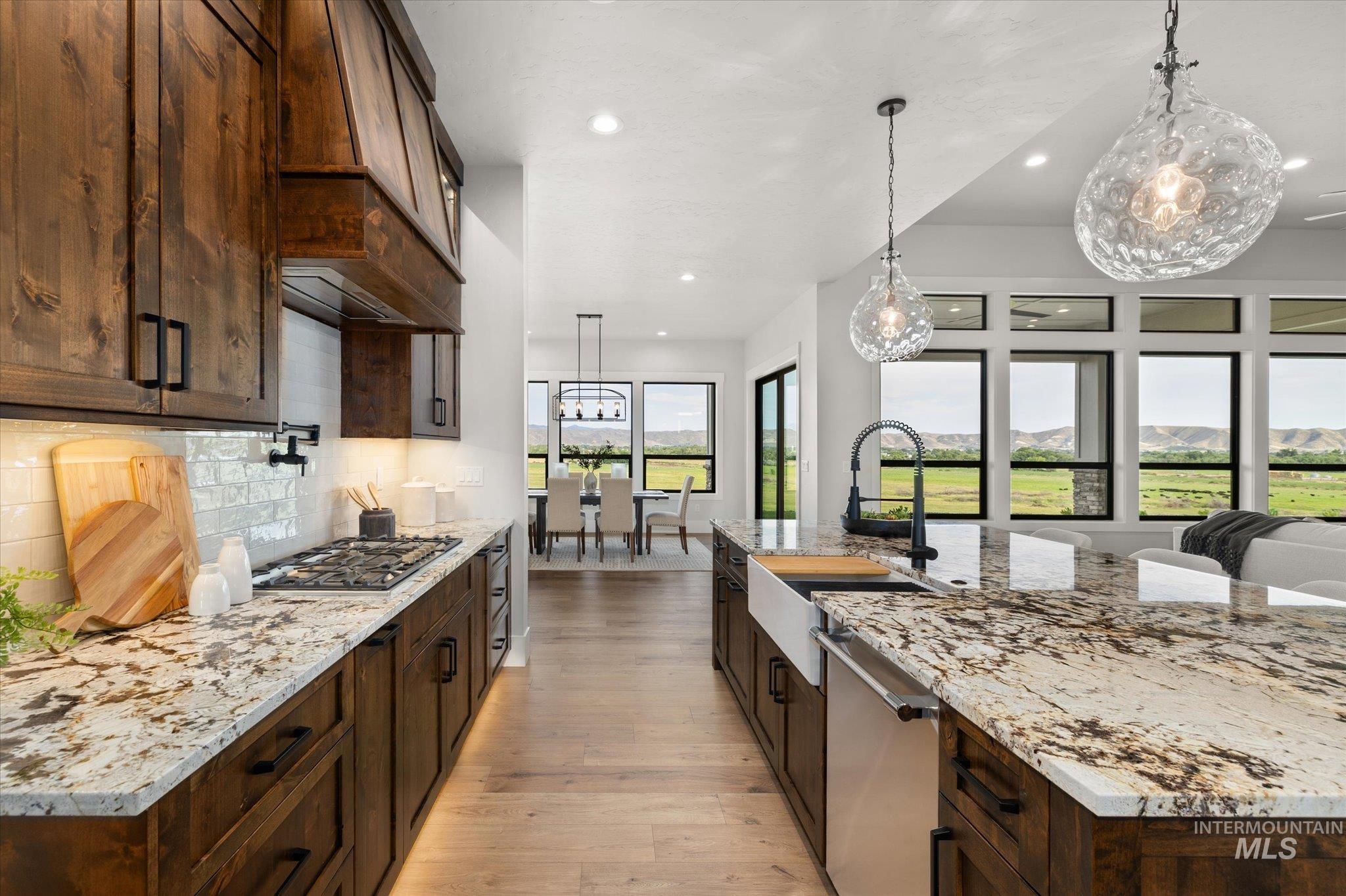 Kitchen featuring light stone counters, pendant lighting, light wood-style flooring, and recessed lighting