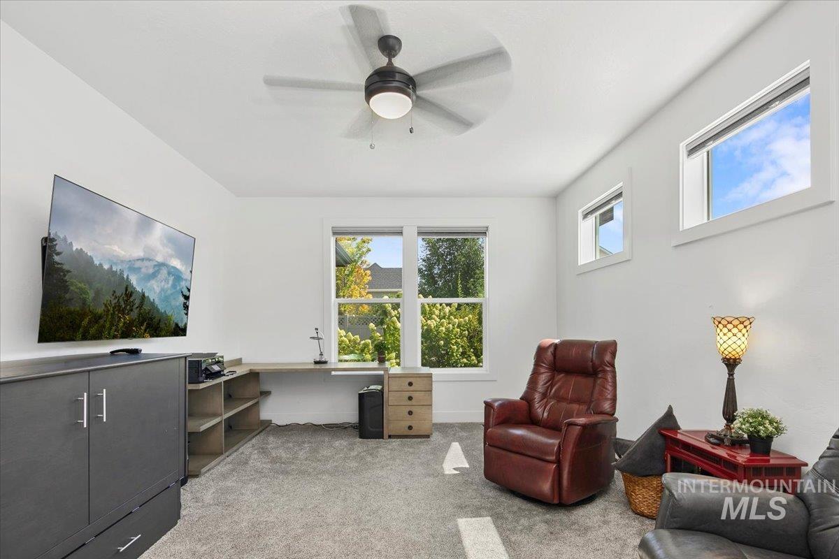 Sitting room with light carpet, ceiling fan, and a desk