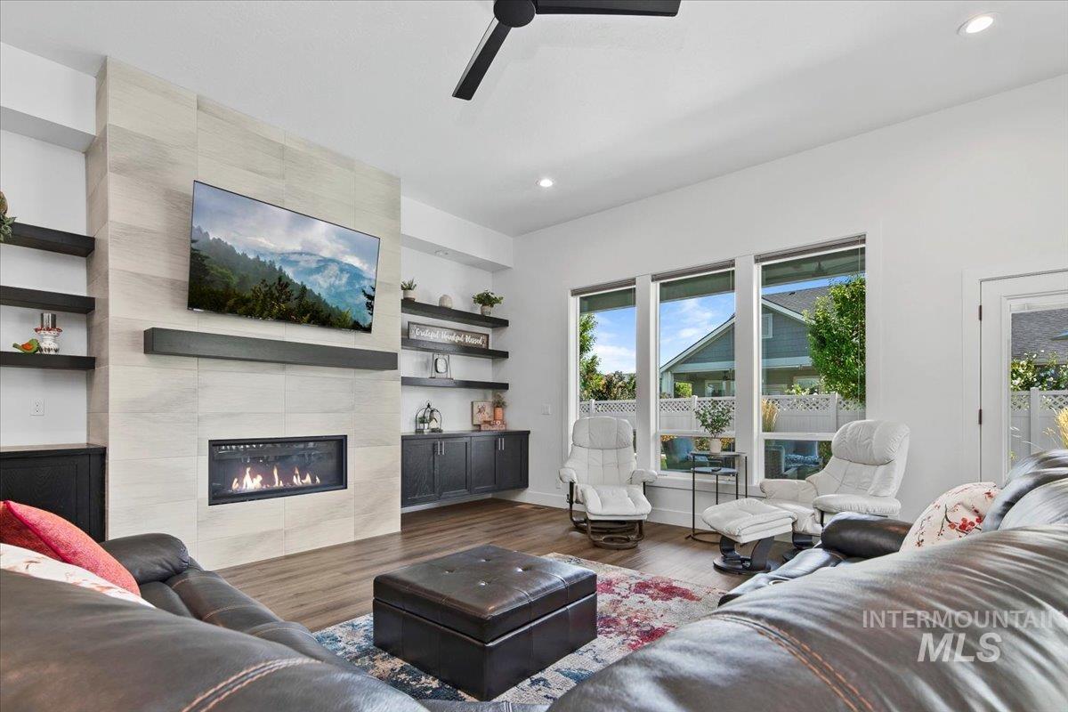 Living area featuring wood finished floors, a tiled fireplace, recessed lighting, and ceiling fan