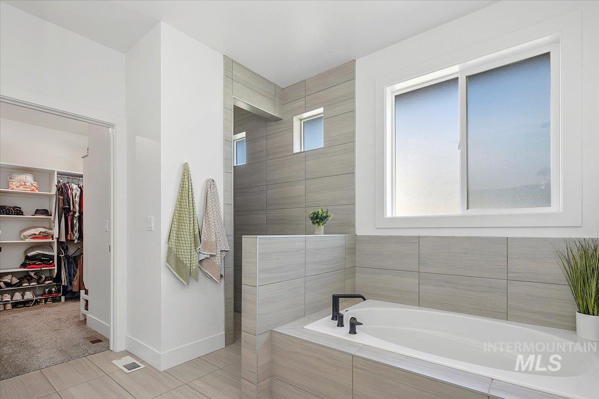 Full bath with a garden tub, a walk in closet, tile patterned floors, and walk in shower