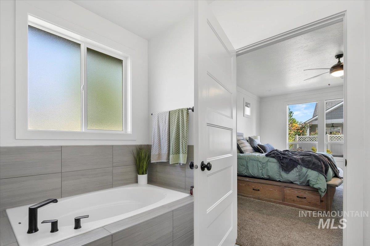 Ensuite bathroom featuring a bath and ceiling fan