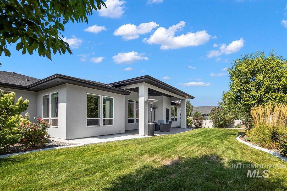 Back of house with stucco siding, a patio, and a yard