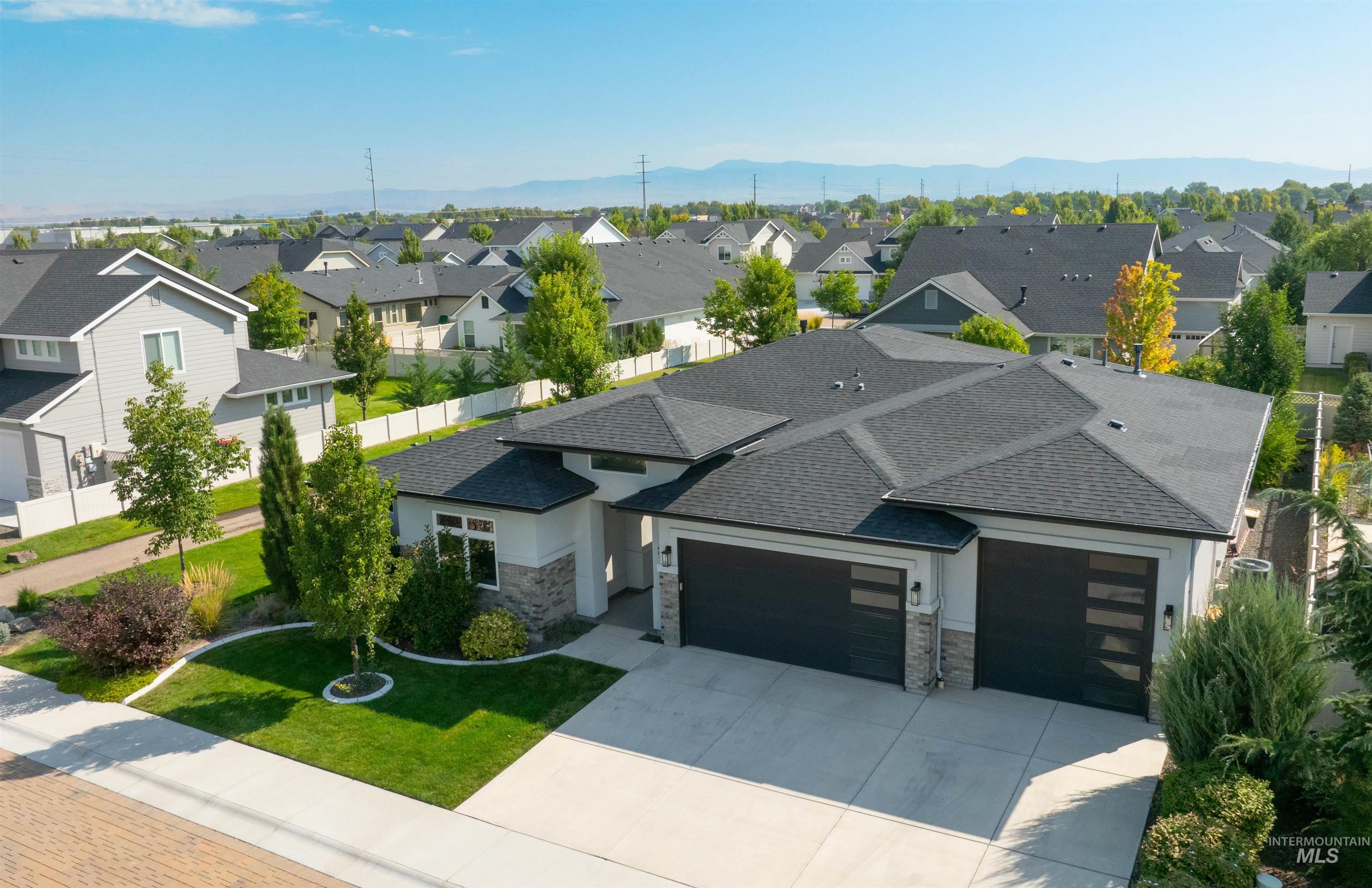 View of front of property featuring a garage, stone siding, driveway, a front yard, and roof with shingles