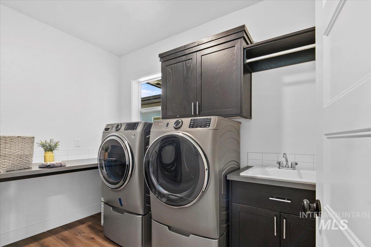 Laundry room with dark wood-style floors, washing machine and dryer, and cabinet space