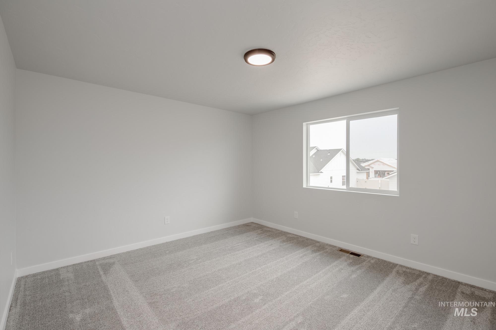Empty room featuring light colored carpet and baseboards