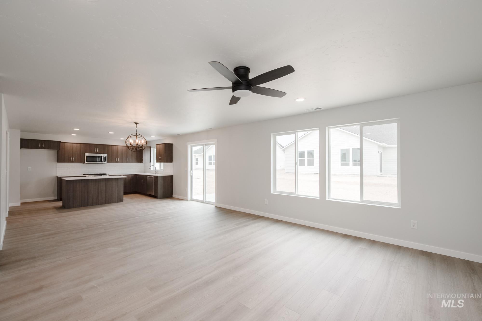 Unfurnished living room featuring a chandelier, light wood-style flooring, recessed lighting, and a ceiling fan