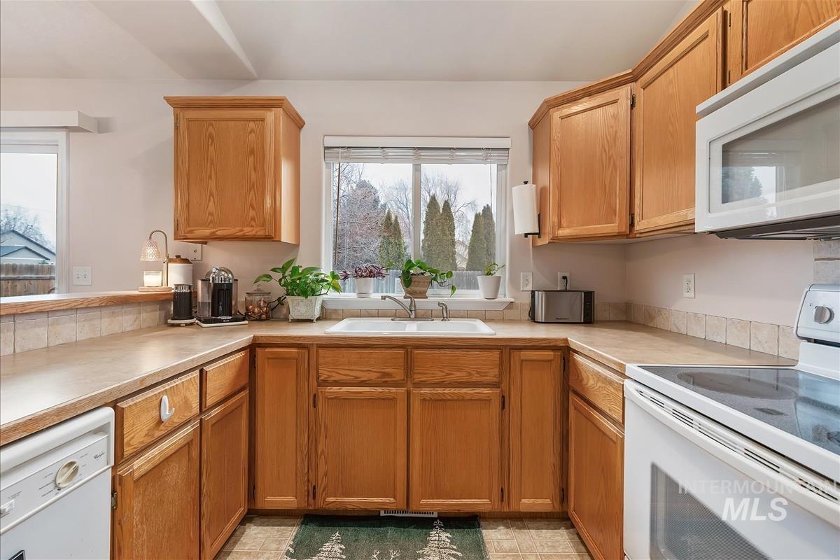 Kitchen featuring white appliances, light countertops, and brown cabinets