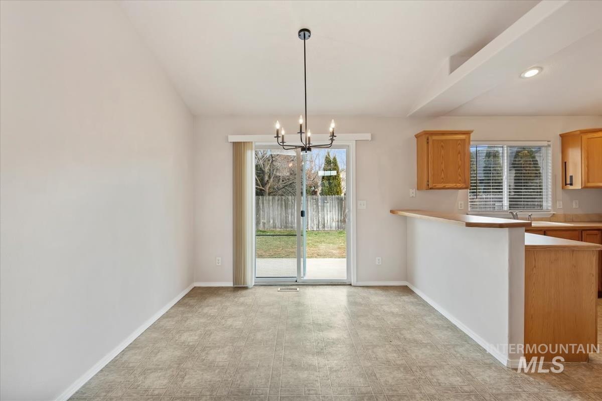 Unfurnished dining area with suspended lighting and baseboards